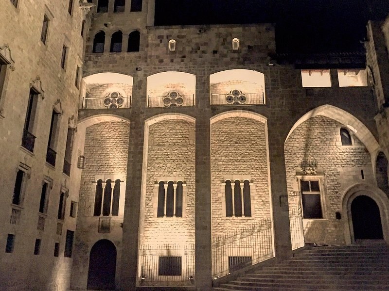 Plaça del Rei floodlit at night, the steps rising to the royal palace